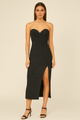Woman wearing a black strapless dress with a slit on a beige background