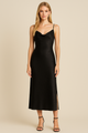 Woman wearing a black slip dress against a beige background