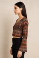Woman wearing a patterned long-sleeve top against a beige background