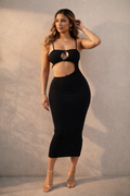 Woman wearing a black dress with cut-out design against a neutral background