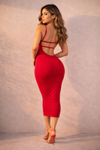 Woman wearing a red dress with cut-out back design against a neutral background