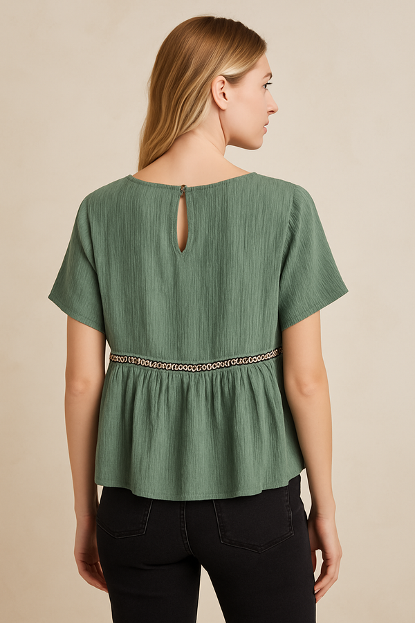 Woman wearing a green blouse with a cut-out back design on a beige background