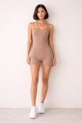 Woman wearing a brown bodysuit against a white background