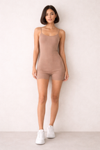 Woman wearing a brown bodysuit against a white background
