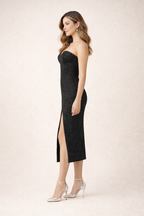 Woman wearing a black strapless dress with a high slit on a white background