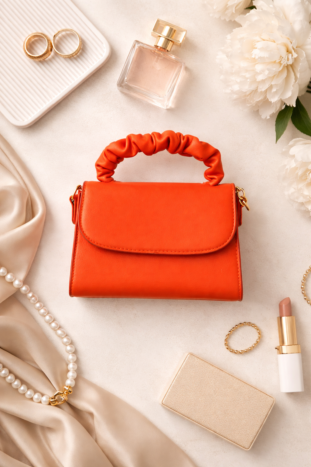 Orange handbag with jewelry, perfume, and makeup on a light background
