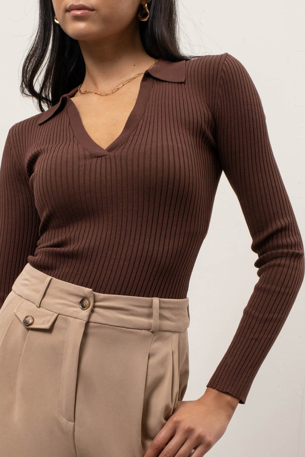 Brown ribbed long-sleeve top worn by a person on a plain background