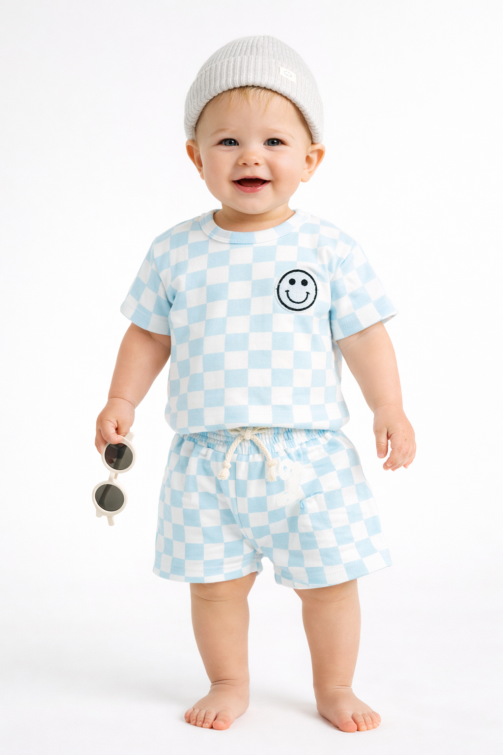 Baby wearing a checkered outfit with a smiley face on a white background