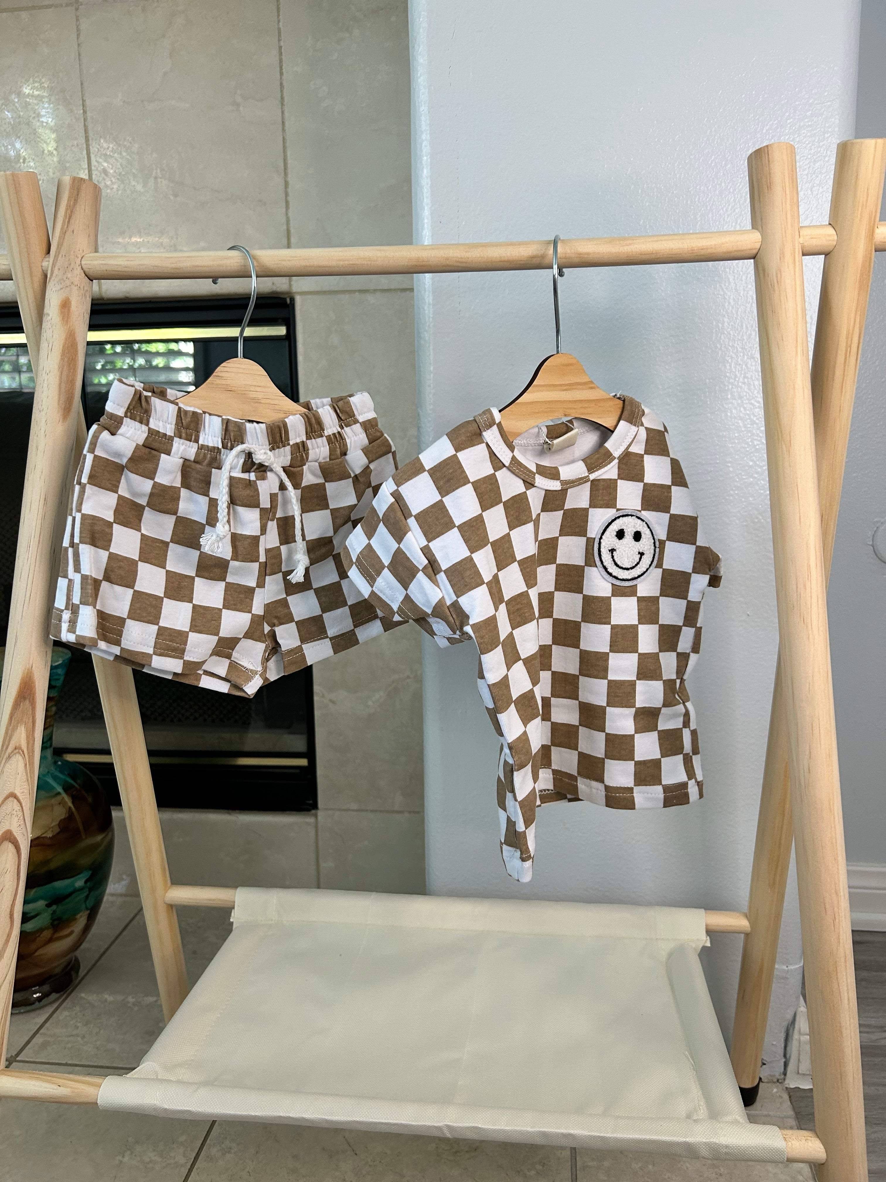 Checkered shirt with a smiley face design hanging on a wooden rack.