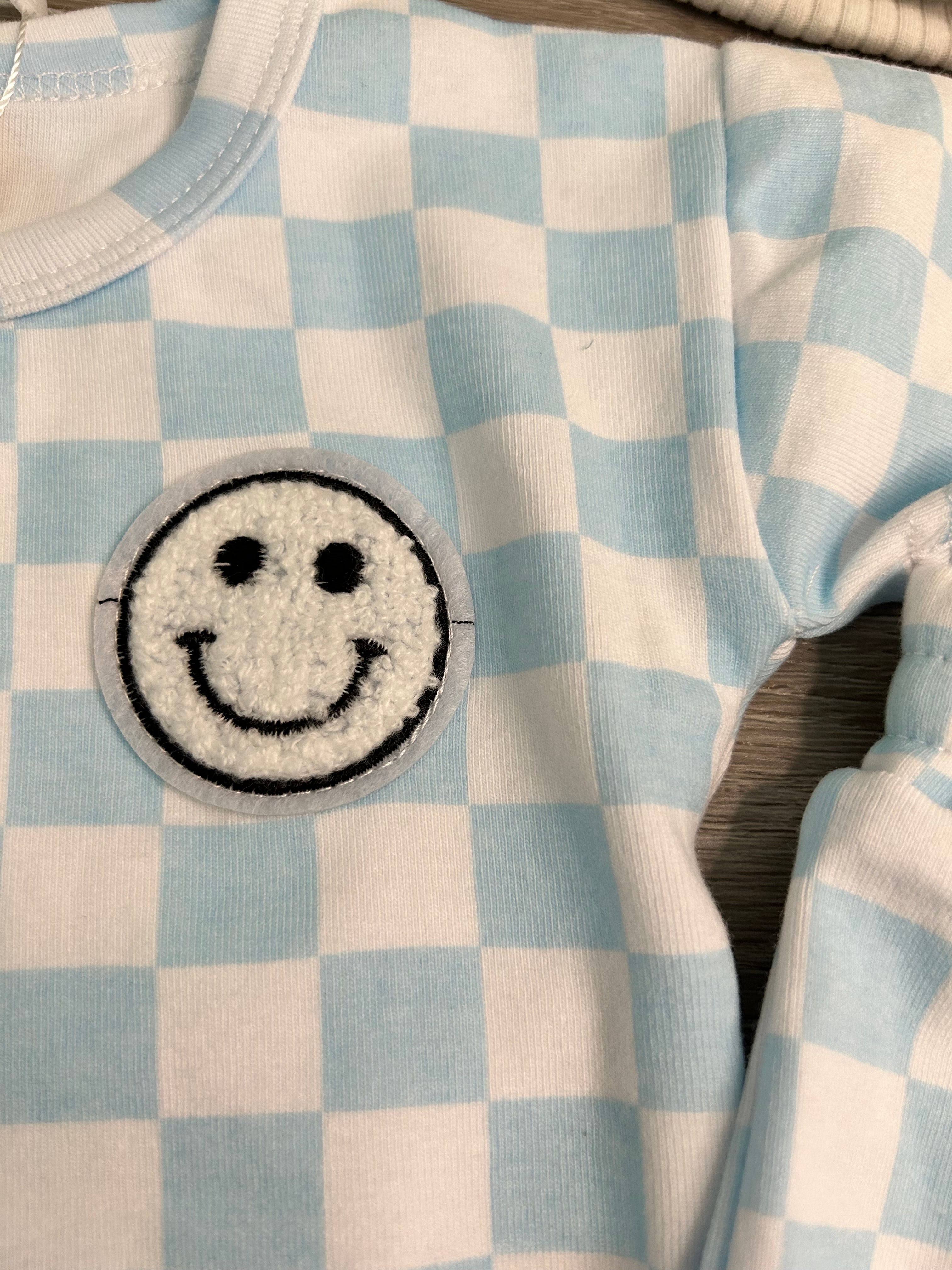 Checkered fabric with a smiley face patch on a wooden surface