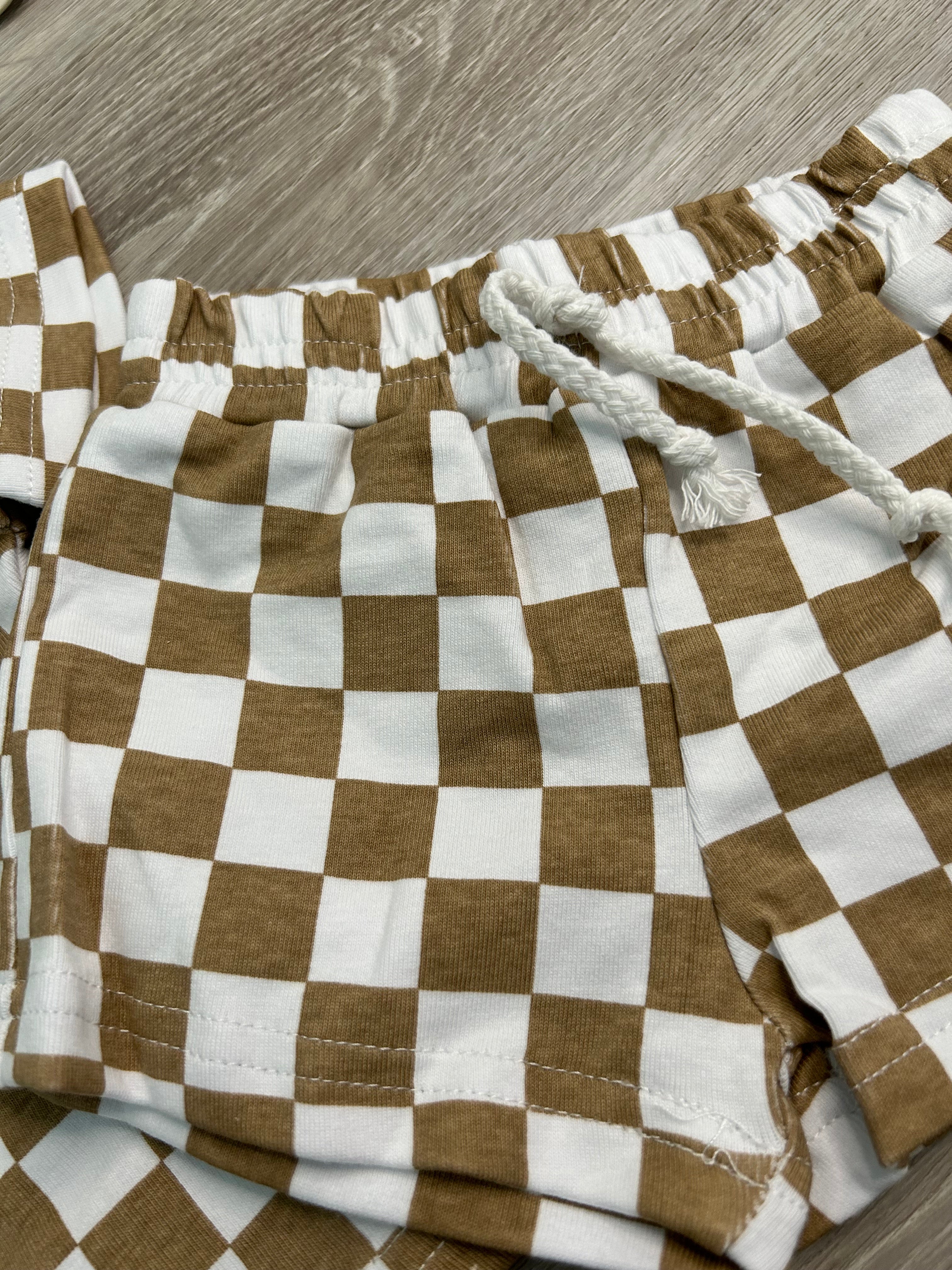 Brown and white checkered towel with rope handle on a wooden surface