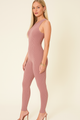 Woman wearing a mauve jumpsuit on a beige background