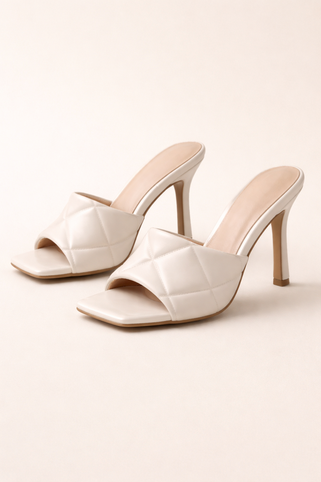 Pair of white high-heeled shoes on a light background