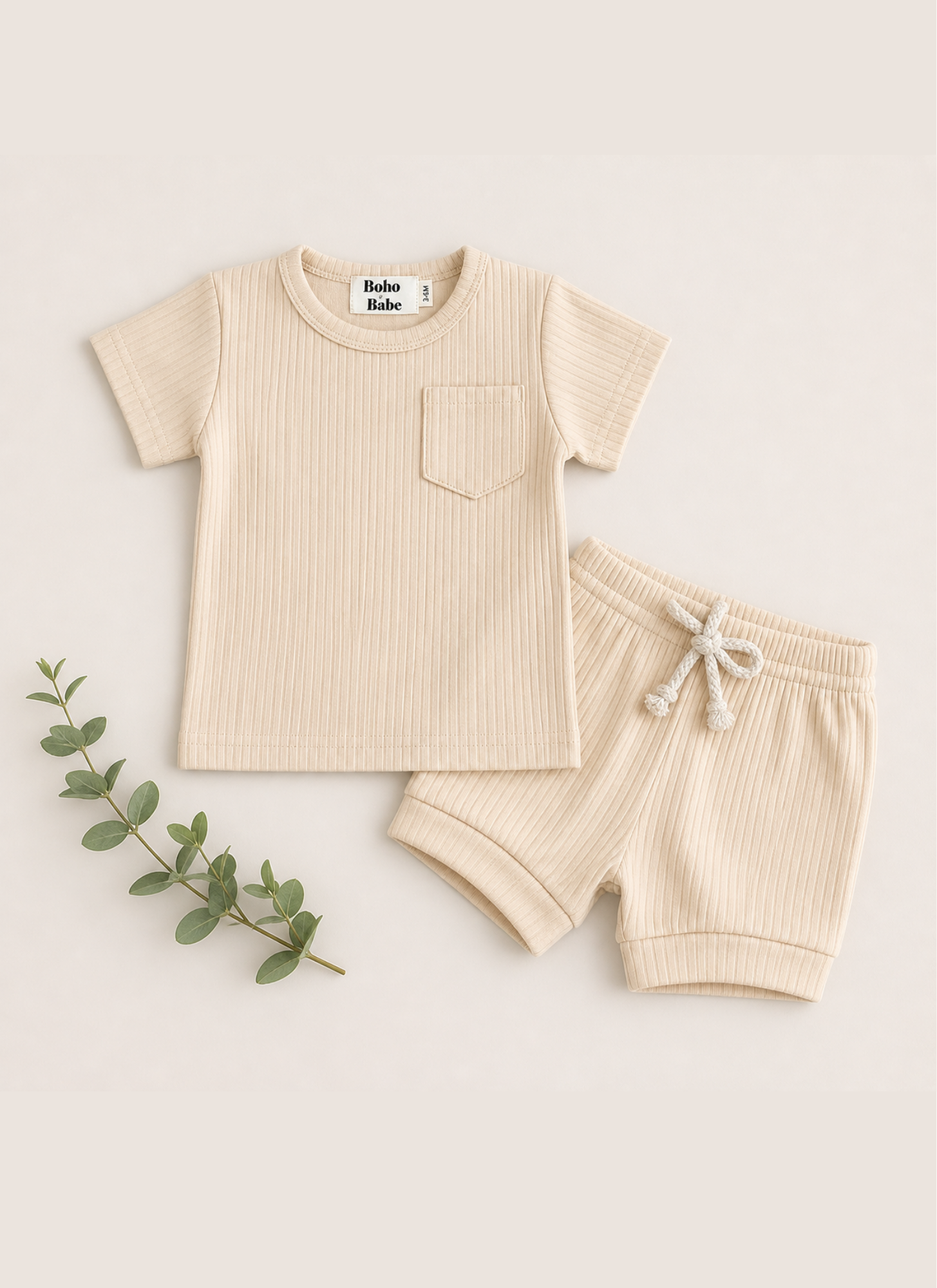 Beige children's t-shirt and shorts set with a leafy branch on a light background
