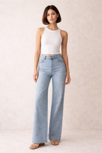 Woman wearing light blue jeans and a white top on a plain background