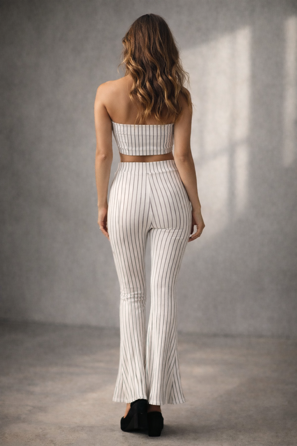 Woman wearing a white pinstripe outfit with a brown belt against a gray background