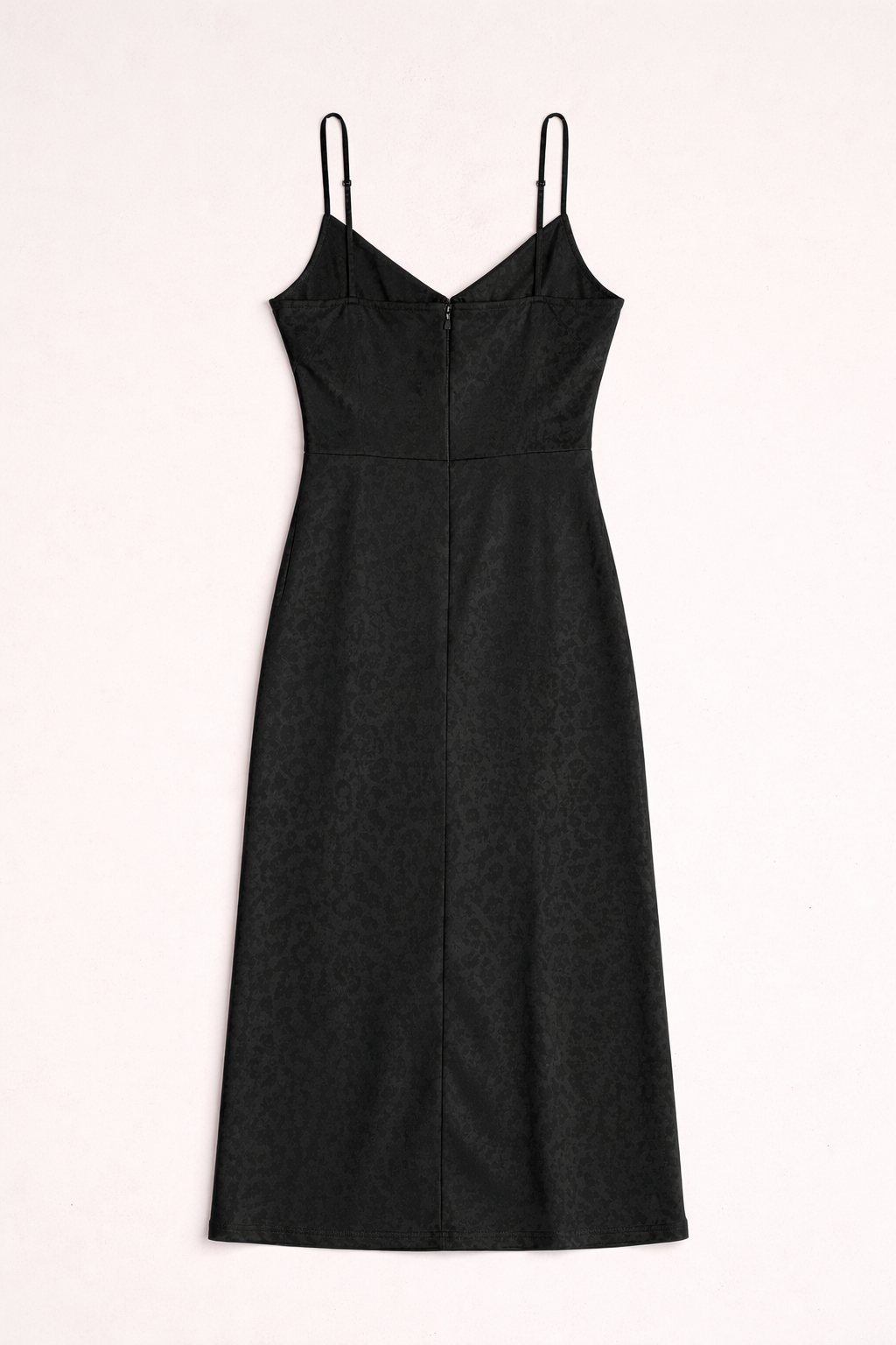 Black dress with thin straps on a light pink background