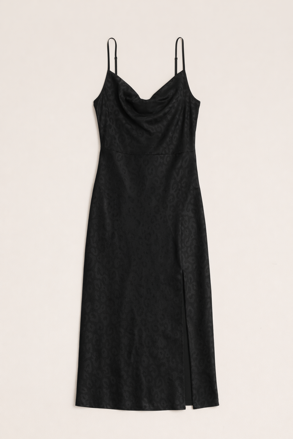 Black slip dress with thin straps on a beige background