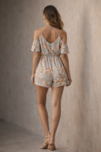 Woman wearing a floral romper against a plain background